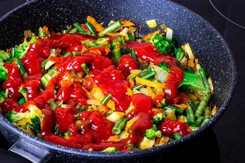 Stewed vegetables in a pan. Cooking process. Vegan food. Stock Photos