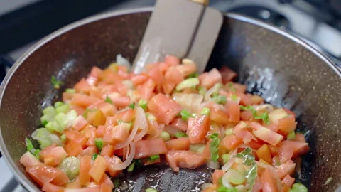Stewing cut fresh red tomatoes, onion, garlic and celery for lunch or dinner Stock Footage 255439950