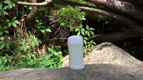 Stick deodorant staying on the stone near green tree with sunlights and shadows Stock Footage