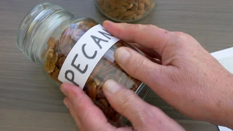 Sticking a label for pecan nuts on a full jar. Stock Footage 143095903