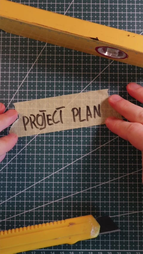Sticking PROJECT PLAN tape label near spirit level. Stock Footage 337816370