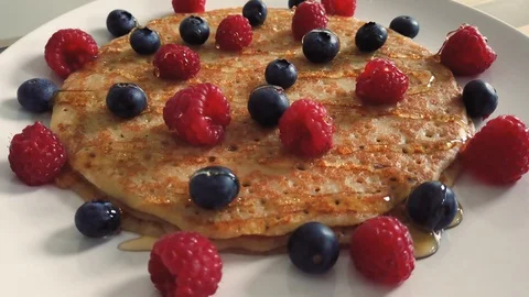 Sticky honey poured over stack of crepes with berries for Candlemas Stock Footage 118451837
