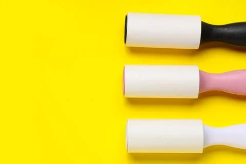 Sticky lint rollers on yellow background Photos