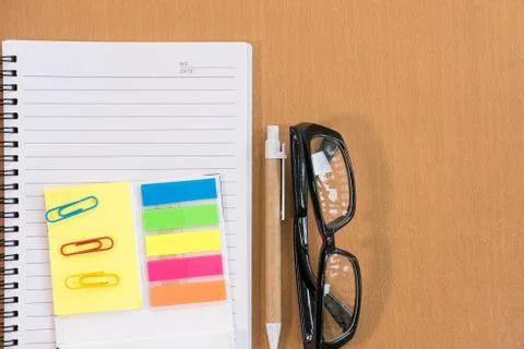 Sticky note, ballpoint pen, empty notebook, eyeglasses on office desk. busine Stock Photos