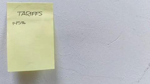 Sticky note emphasizing tariffs on a textured white background, symbolizing.. Stock Photos