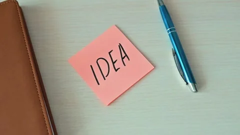 Sticky note on a flat surface with the word idea written clearly in bold letters Stock Footage 339094105