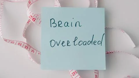 Sticky note with handwritten text on brain overload surrounded by measuring.. Stock Photos
