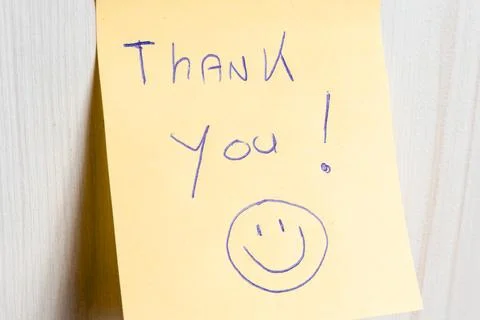 A sticky note hanging on the wall, with the text Thank You on it. Stock Photos