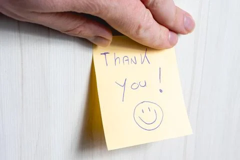 A sticky note hanging on the wall, with the text Thank You on it. Stock Photos