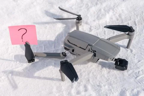 Sticky note with question mark in propeller blades of broken drone on snow Stock Photos