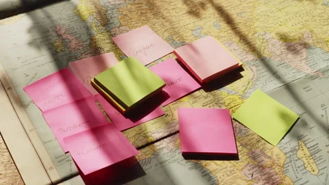 Sticky note reminders cascade onto a travel map in slow motion, symbolizing Stock Footage 337761988