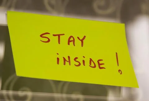 Sticky note on window with Stay Inside writing text message Foto stock