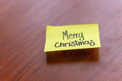 Sticky note on a wooden table desk background. written note text is merry c.. Stock Photos