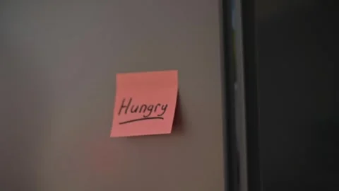 A sticky note with the word 'Hungry' is attached to a black surface in a Video stock 339096419