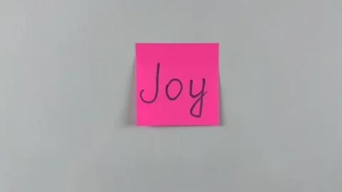 Sticky note with word Joy written on it, pinned on white background 스톡 동영상 305329651