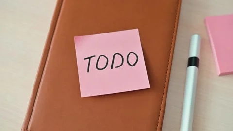 A sticky note with the word TODO is placed on a notebook, alongside a pen. Stock Footage 339094082
