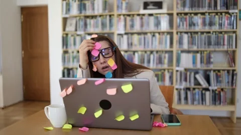 Sticky notes cover an overworked office employee and her laptop as she struggles Stock-Footage 342178414