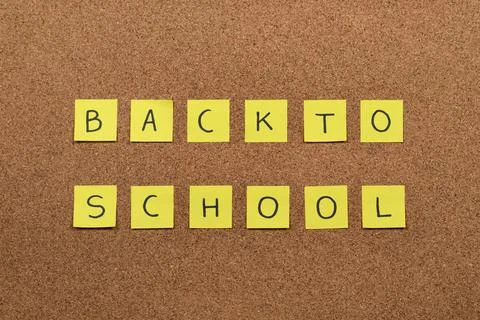 A sticky notes handwriting with the phrase back to school over a cork backg.. Stock-Fotos