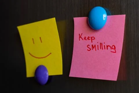 Sticky notes keep smiling and smiley magnet attached to the refrigerator. Stock Photos