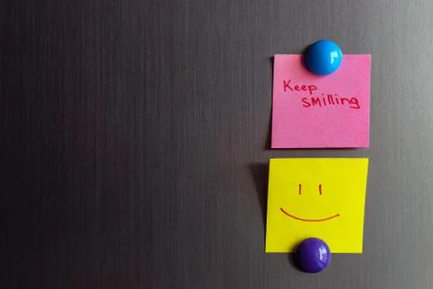 Sticky notes keep smiling and smiley magnet attached to the refrigerator. Stock Photos