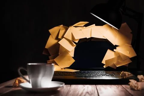 Sticky notes overflow a laptop under a lamp in a late burnout scene Stock Photos
