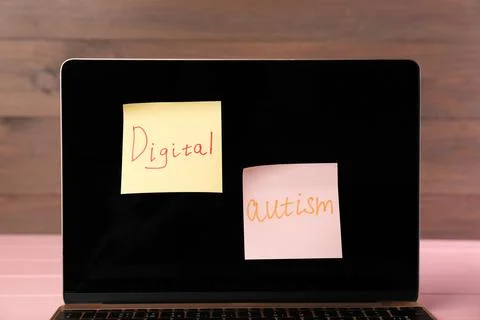 Sticky notes with phrase Digital Autism attached to laptop on table, closeu.. Stock Photos