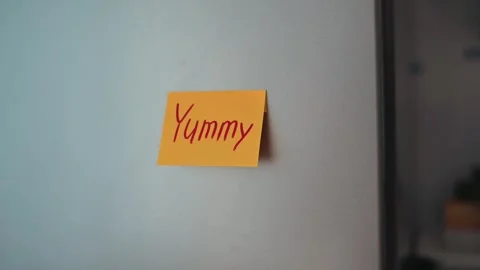 Sticky notes stating Yummy are placed on a refrigerator in a kitchen. The Stock Footage 339096373