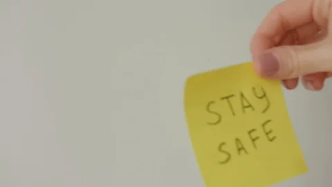 Sticky notes Stay safe and Stay home being sticked to white surface Stock Footage 128058954