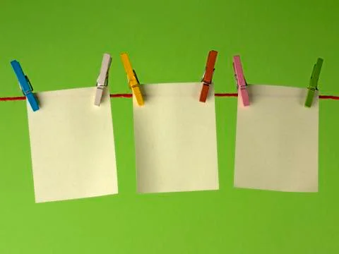 Sticky yellow papers notes hanging on clothes peg, on a green background. Foto stock