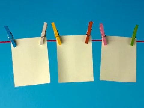 Sticky yellow papers notes hanging on clothes peg, on a blue background. Foto stock