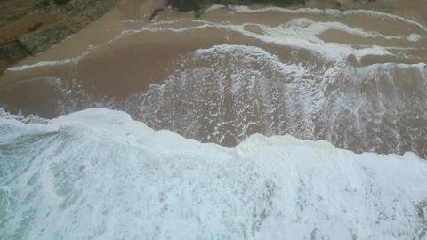 Still aerial image of waves breaking on the sand. The sea is white due to foam 動画素材 331066571