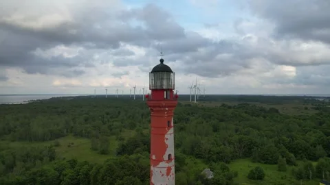 Still aerial video of a lighthouse with a wind farm behind it Video stock 257133395
