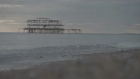 Still close up shot of small waves washing up onto shoreline with old pier Stock Footage 202133479