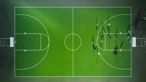 Still drone above team of athletic people playing basketball game after sunset Vidéo 245524974
