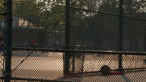 Still of fenced in New York City park with basketball on ground, day. Stock Footage