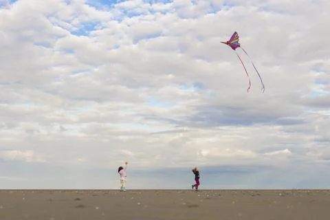 Still image of two children chasing kites have fun on the beach. Stock Photos