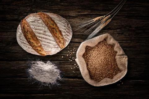 Still life with baking rye bread, ears, flour and bag of grains in a sackclot Stock Photos