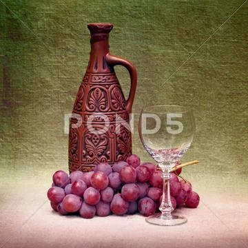 Still-life with clay bottle, glass and grapes against canvas Stock Photos