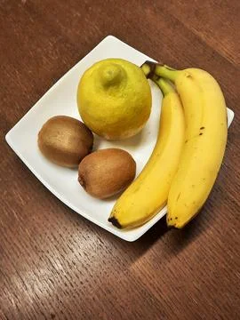 Still life composition with two bananas, one lemon and two kiwis Stock Photos
