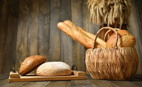 Still life with fresh various breads in a wicker basket on a wooden background Stock Photos
