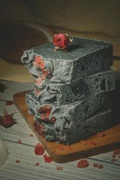 Still life of a handmade soap stack with a dry rose bud on a wooden board. Focus Stock Photos