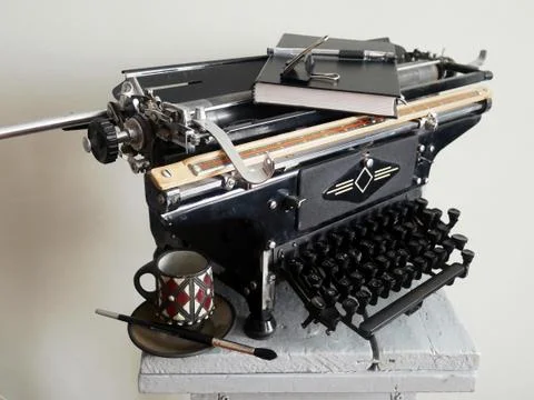 A still-life of old black objects: a typewriter, a book and a coffee cup Stock Photos