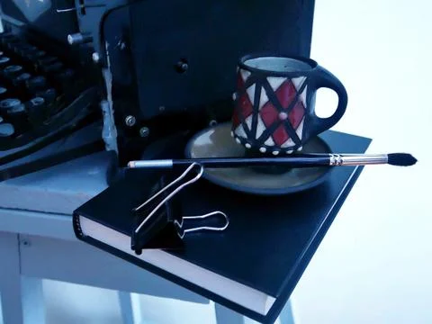 Still-life of old black objects: a typewriter, a book and a coffee cup Stock Photos