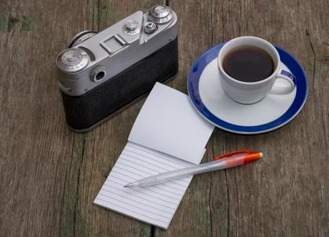 Still life the old camera, a notebook and coffee, on an old table Stock Photos
