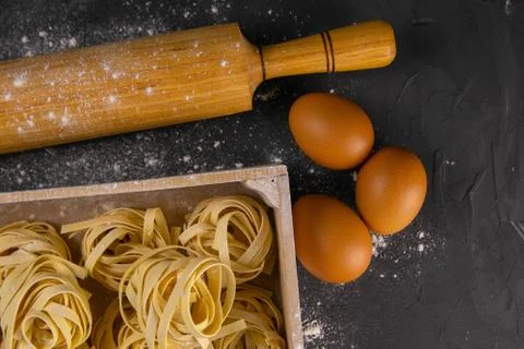 Still life of preparing pasta on rustic wooden background. Raw tagliatelle in Stock Photos