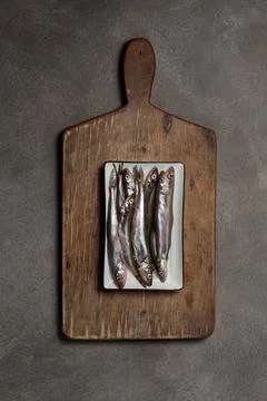 Still life with raw fish on a rustic wooden board. Top view. Stock Photos