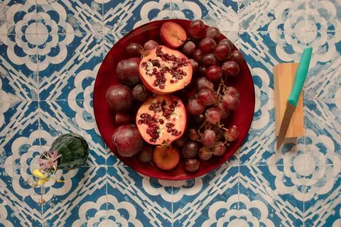Still life raw plums, pomegranate and grapes in a vintage background Stock Photos