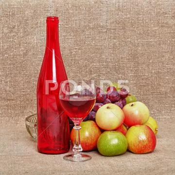 Still-life - red bottle of wine and fruit against a canvas Stock Photos