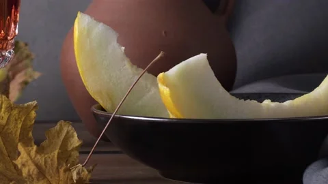 Still life with sliced melon, a clay jug of wine and autumn leaves Stock Footage 138637480