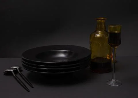 Still life. A stack of black plates, round designer spoons with black handl.. Stock Photos